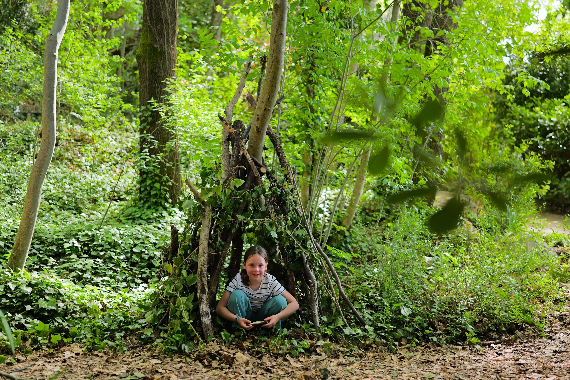 Une enfant dans une cabane de bâtons dans la forêt d'Orion